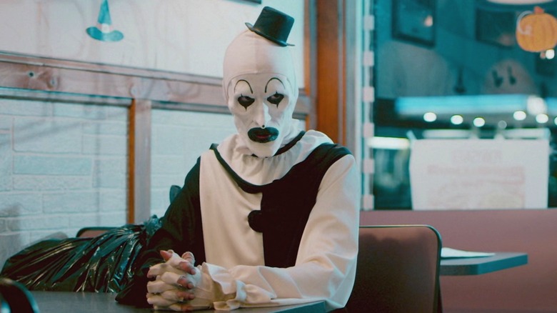 Art the Clown sitting at a booth in 