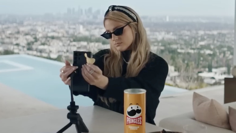 Meghan Trainor holding a chip and fixing her phone