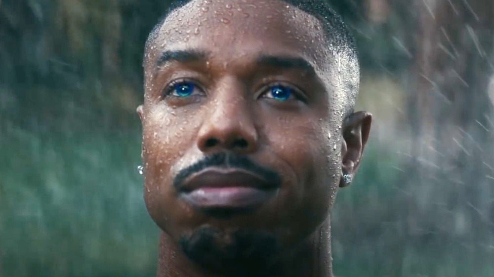 Michael B. Jordan with blue eyes getting sprayed by sprinklers