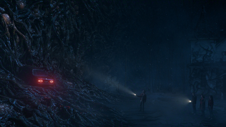 The gang holding flashlights looking at a car stuck in the Upside Down in Stranger Things 5
