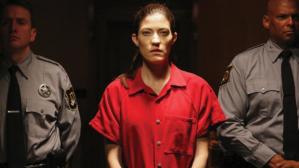 Woman glowering wearing prison jumpsuit