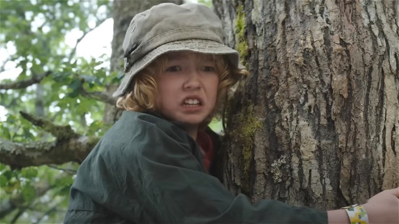 A kid hiding in a tree in Cocaine Bear 