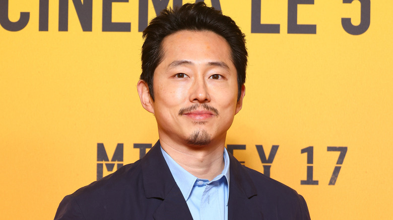 Steven Yeun smiling at the French premiere of "Mickey 17" in 2025