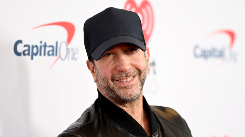 David Schwimmer, in baseball cap and beard, turns to smile