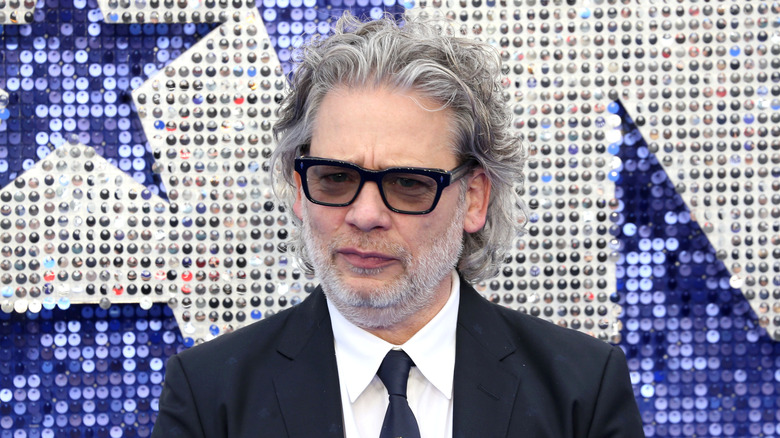 Dexter Fletcher stands against a glittery background