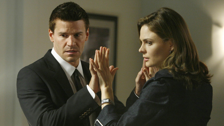 Bones and Booth touch hands through a two-way mirror in "Bones"