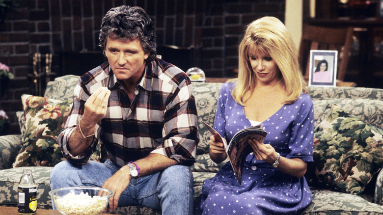 Carol reading a magazine while Frank Lambert eats popcorn on the couch