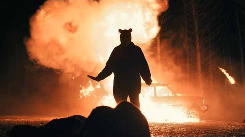 Pooh standing silhouetted in front of flames