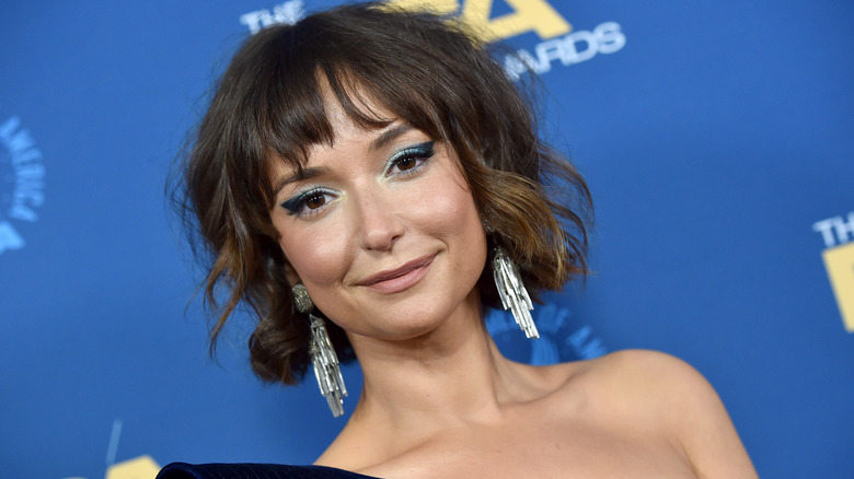 Milana Vayntrub smiling with silver dangling earrings