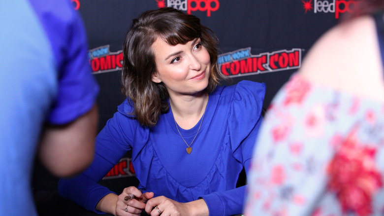 Milana Vayntrub smiling at table at Comic-Con