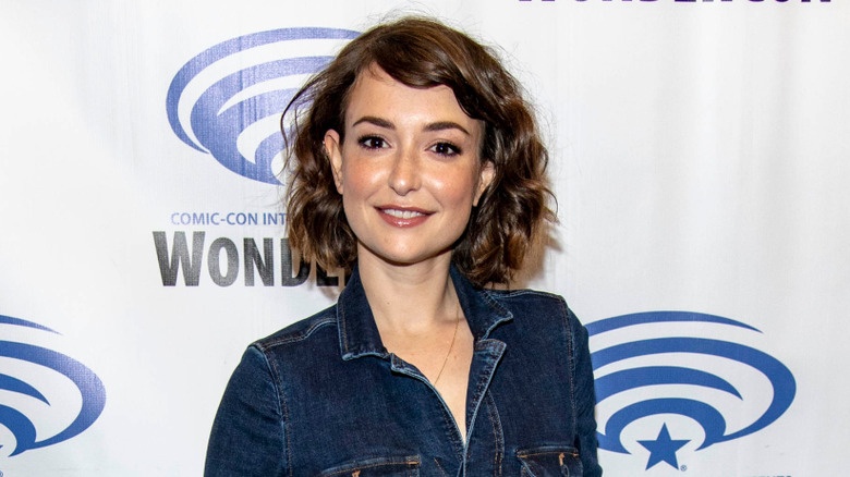 Milana Vayntrub smiling wearing denim dress