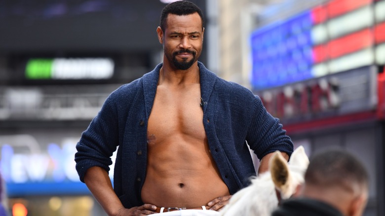 Isaiah Mustafa in an open cardigan riding a horse in Times Square