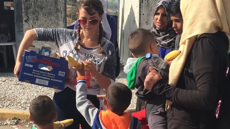 Milana Vayntrub menyerahkan pisang kepada anak -anak