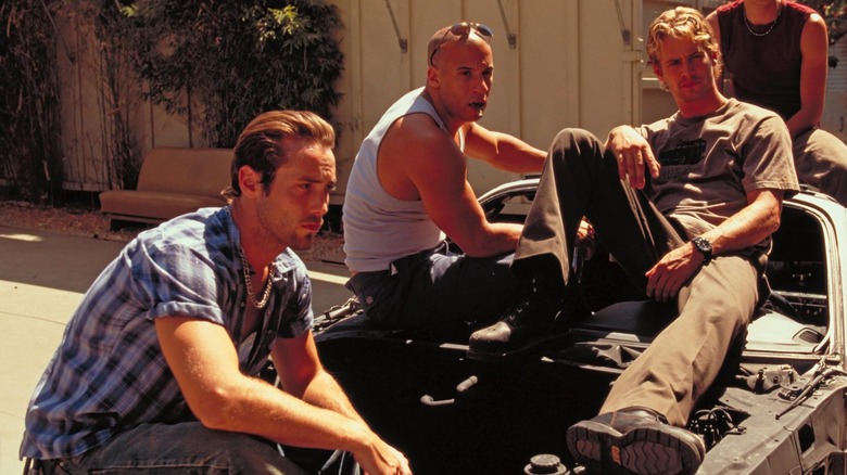 Leon, Dom, and Brian sitting on car