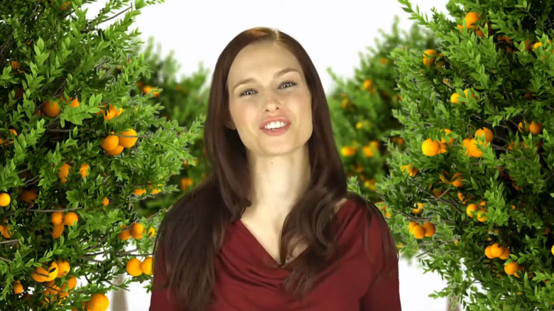 A smiling woman in an orange grove promotes C-Spray for Marz Sprays