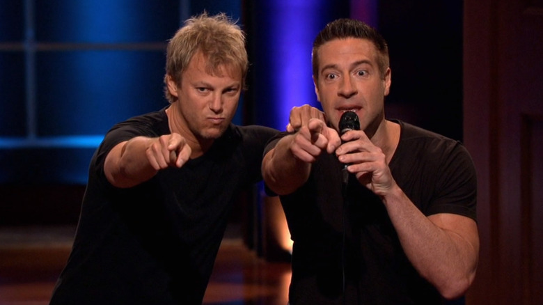 Eric Berkowitz and John Devecka holding microphone and pointing