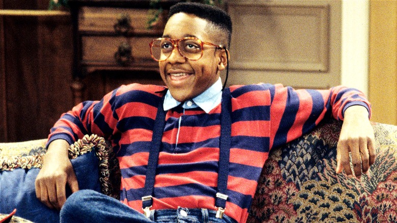 Steve Urkel smiling goofily on the couch in Family Matters