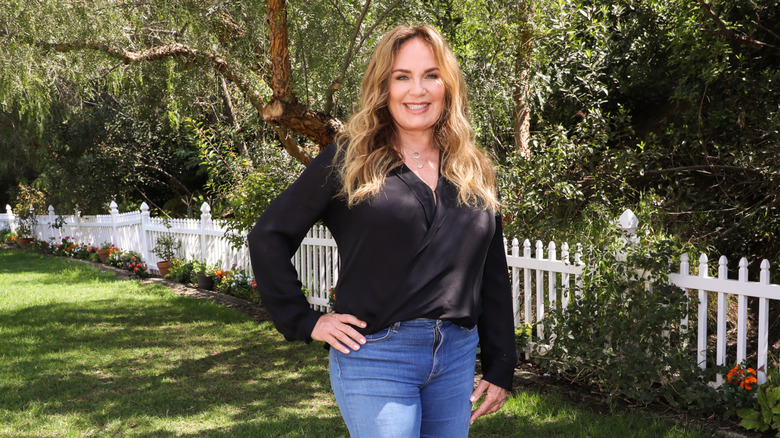 Catherine Bach smiles and stands with a hand on her hip