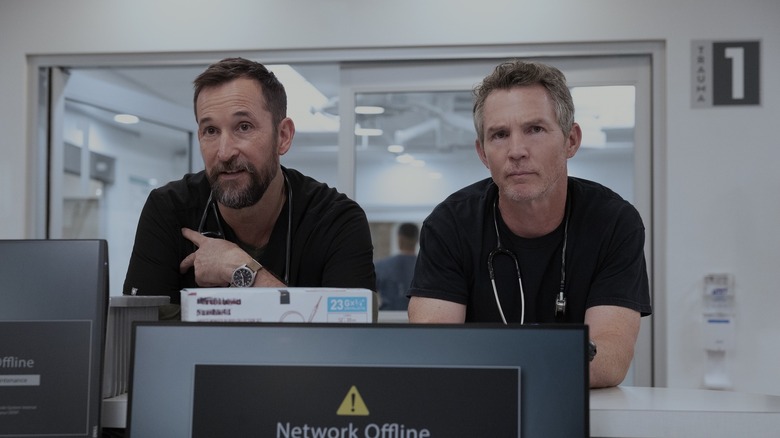 Robby and Dr. Abbot frowning while leaning against a counter in 