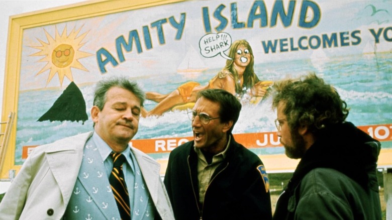 Hooper and Brody speaking to the mayor next to an Amity Island billboard in 