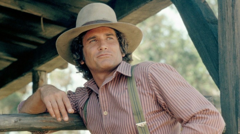 Charles Ingalls leaning against a fence in 