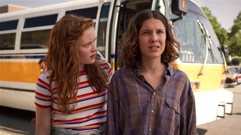 Max and Eleven standing in front of bus in "Stranger Things" (2016-2025)