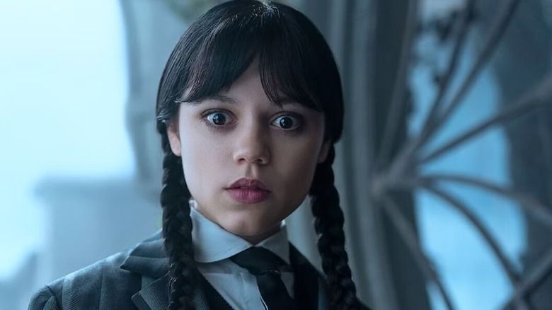 Wednesday stares in front of an open window in "Wednesday."