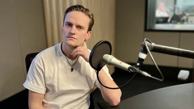 Performer Arnmundur Ernst Björnsson sitting at a podcast microphone