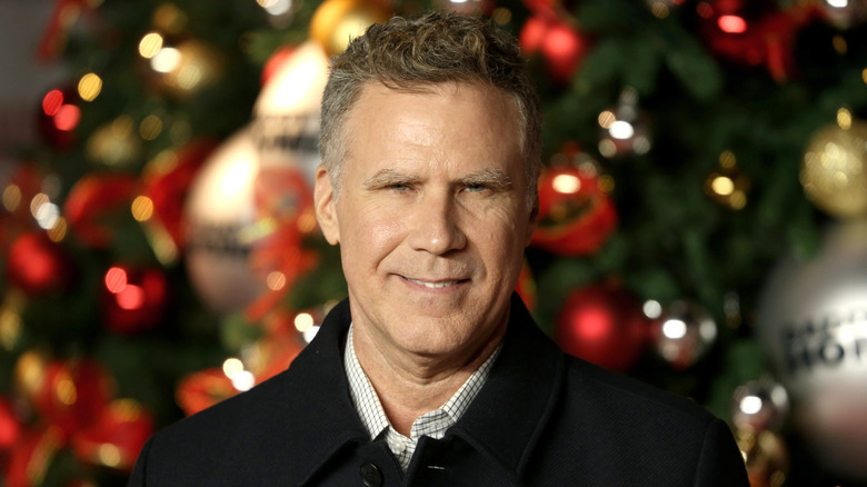 Will Ferrell smiling in front of a Christmas tree
