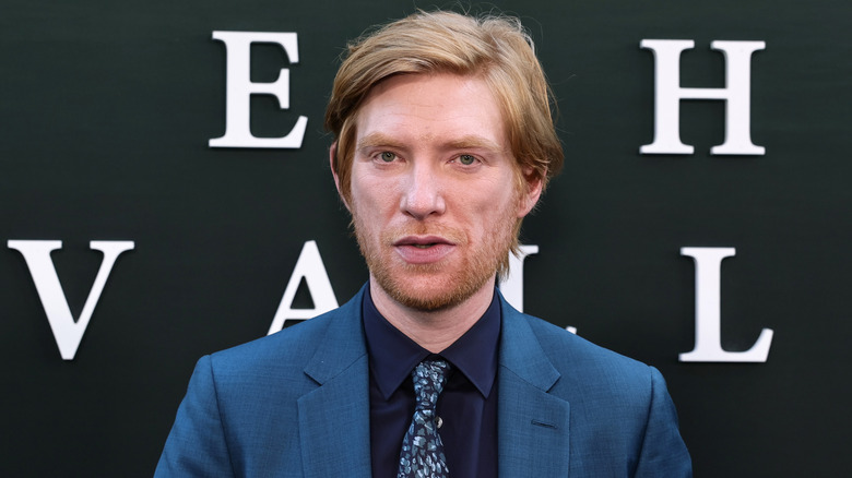 Ireland-born actor Domhnall Gleeson posing in front of a black wall with white letters