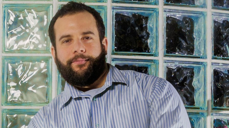 Actor and comedian Eric Rahill leaning against a glass block wall
