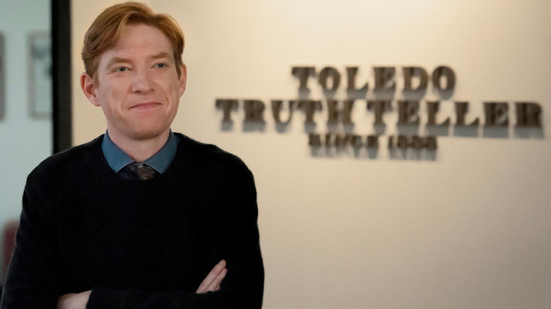 Editor-in-chief Ned Sampson (Domhnall Gleeson) standing in front of a wall sign that reads 
