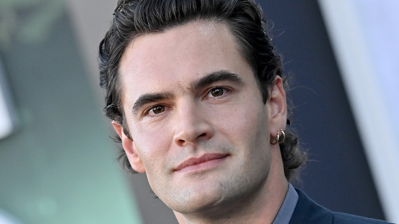 Tom Bateman with two earrings