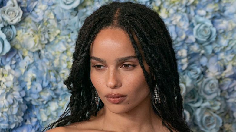 Zoe Kravitz near wall of blue flowers