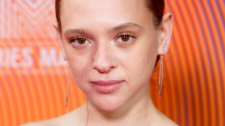 Shira Haas poses in front of an orange background