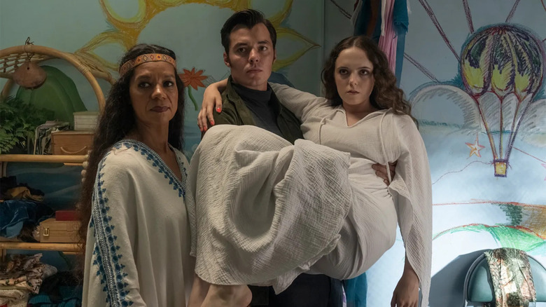 Sister Susie standing next to Alfred Pennyworth holding Jessica Thistle in his arms