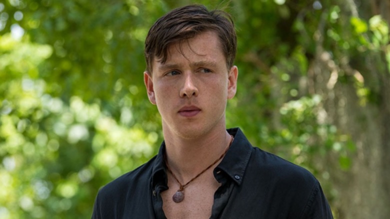 Chase Andrews with an open shirt in the woods