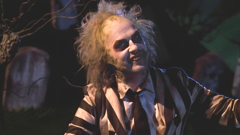 Beetlejuice raises his arms and smiles 