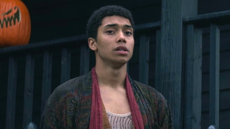 Ambrose Spellman standing next to two pumpkins