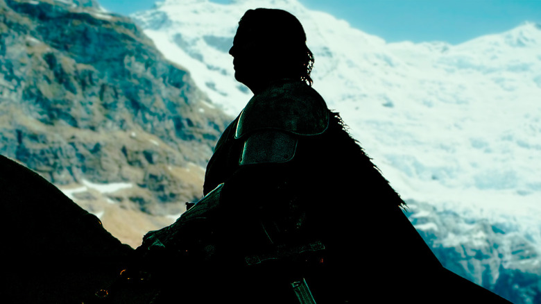 A silhouette of a man on a horse with a mountain behind him