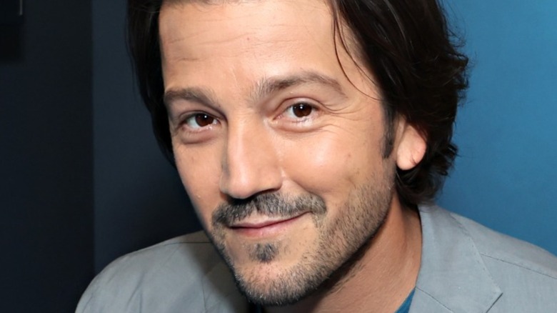 Diego Luna smiling in front of a dark blue background