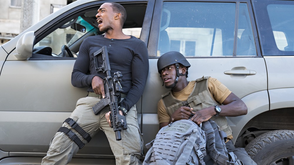 Anthony Mackie and Damson Idris take shelter behind a vehicle