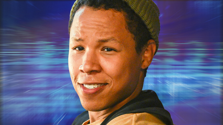 Bobby Exley smiling and wearing a beanie against a blue background