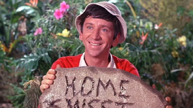Gilligan smiling with a carved rock reading 