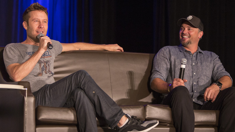 Michael Rosenbaum and Tom Welling sitting on stage on a couch