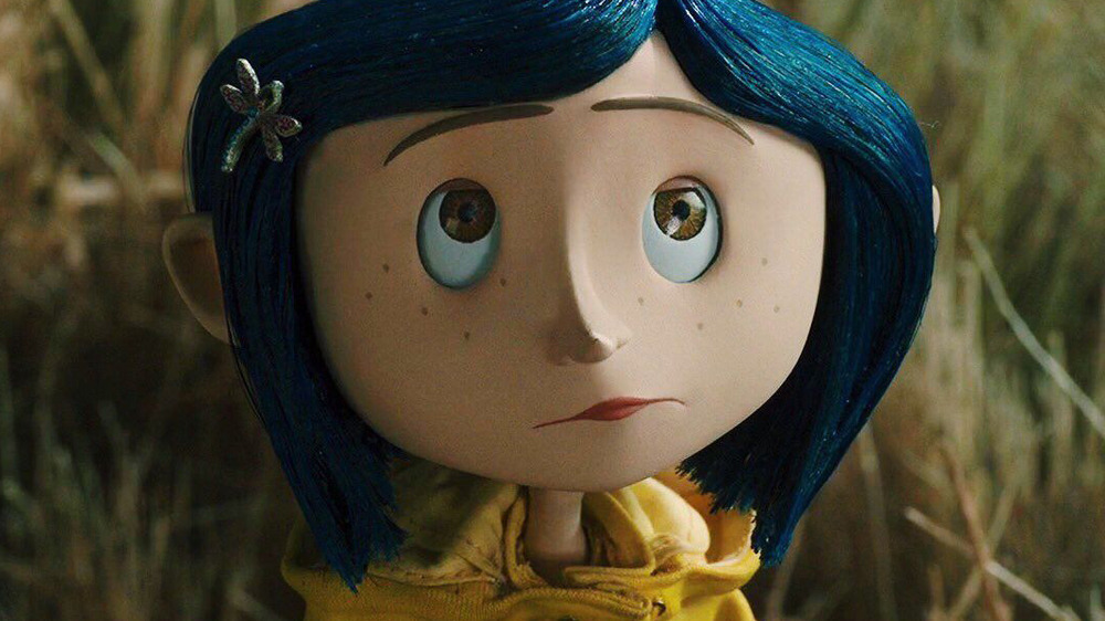 Coraline in yellow raincoat looking up at something in Coraline