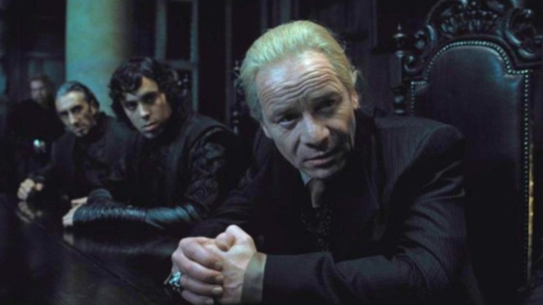 Mullan as Yaxley in a suit with platinum blonde hair