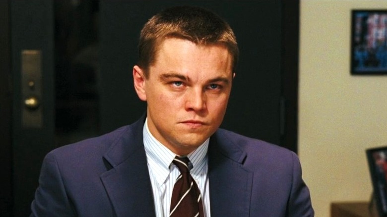 DiCaprio sits in front of a desk