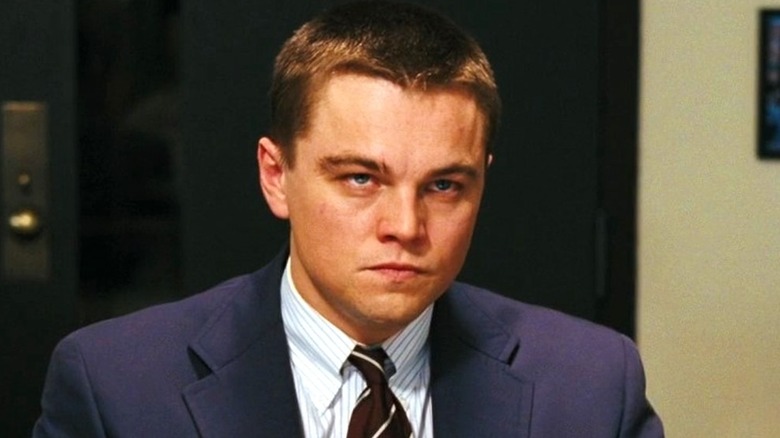 DiCaprio sits in front of a desk