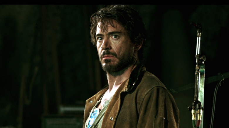 Tony Stark looking worried as a captive with overgrown hair and beard